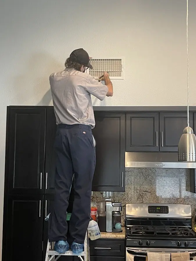 Technician inspecting an air vent during HVAC service in Bardmoor